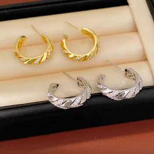 Detail of gold and silver plated C-shaped hoop earrings with sparkling zircon stones