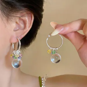 Primo piano di orecchini a cerchio in argento con perline e sfera di cristallo.