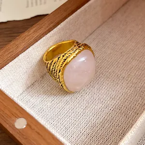 Close-up of a vintage gold ring with a large square rose quartz stone on textured fabric.