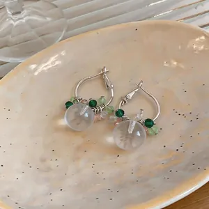 Primo piano dettagliato di orecchini a cerchio in argento con perle opache e tocchi verdi