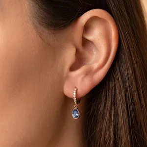 Détail d'une boucle d'oreille plaquée or 18 carats avec pendentif zircon bleu.