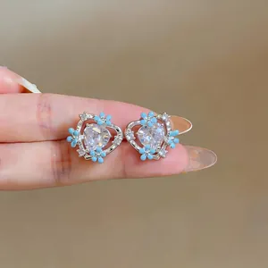 Detailed view of silver heart earrings featuring sparkling crystals and blue flowers