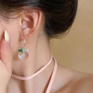 Primo piano di eleganti orecchini a sfera di vetro rotondi con perline verdi su modella