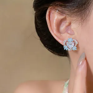 Detailed view of silver heart stud earrings with blue enamel flowers and clear stones