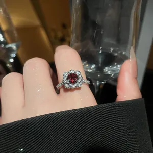 Close-up of sparkling flower ring featuring a vibrant red center stone and zircon petals.