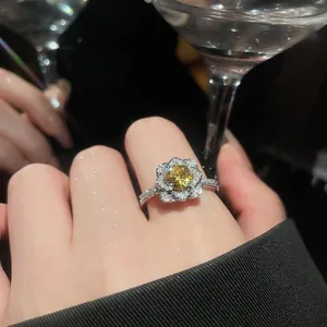 Close-up of a sparkling flower ring with a bright yellow zircon center stone on a finger.