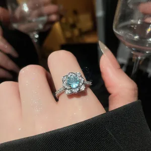 Detail shot of a flower-shaped silver ring featuring a sparkling blue center stone.