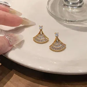 Dettaglio di orecchini a clip a ventaglio placcati in oro con zirconi scintillanti