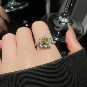 Detailed macro view of a floral silver ring with yellow zircon worn on an index finger