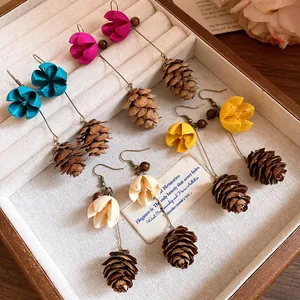 Close-up of vintage forest-style pinecone and flower drop earrings in a box