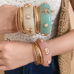 Detailed view of bohemian resin starfish and pearl bangles set worn by a model