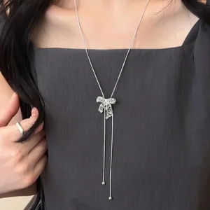 Detailed shot of an intricate hollow bow pendant necklace on a delicate silver chain