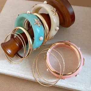 Detail of Bohemian resin bangles with starfish and pearl accents on wooden display