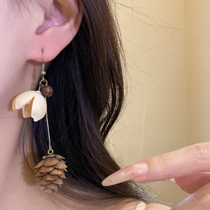 Detailed view of vintage forest-style hazelnut and flower drop earrings on a model