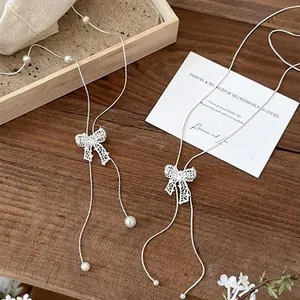 Detail shot of elegant hollow bow necklace with pearl accents on wooden background