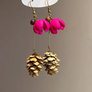 Detail of forest style drop earrings featuring pink flowers and pinecone pendants