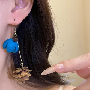 Close-up detail of forest-style hazelnut plant pendant drop earrings worn by a model