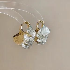 Nahaufnahme eleganter Ginkgoblatt-Ohrringe mit strukturierter Gold- und Silberoberfläche