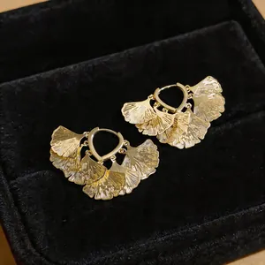 Detailaufnahme goldener fächerförmiger Ginkgoblatt-Ohrringe auf feinem schwarzen Samthintergrund