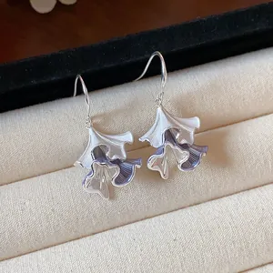 Vista macro dettagliata di eleganti orecchini a foglia pieghettata con smalto viola a goccia