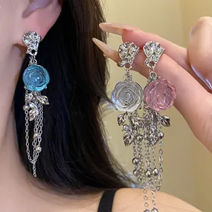 Detailed view of resin rose earrings with long metal tassels, showing worn and hand-held styles.