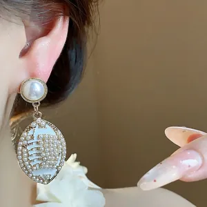 Elegant oval faux pearl drop earrings with silver needle and white enamel detailing