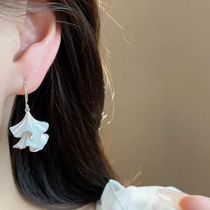 Primo piano dettagliato di eleganti orecchini pendenti in smalto bianco su modella