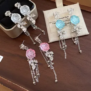 Macro view of elegant resin rose tassel earrings in pink, blue, and clear colors