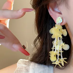 Close-up of elegant yellow fringe earrings with flower sequins and beads.