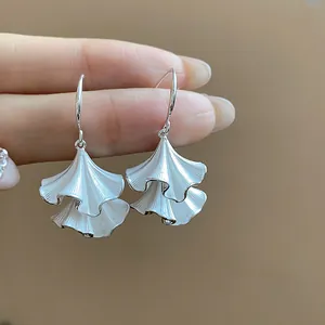 Dettaglio macro di orecchini a foglia argentati con elegante smalto bianco lucido
