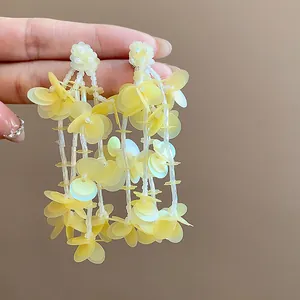 Close-up macro detail of yellow sequin tassel earrings with floral stud and 18k gold plating