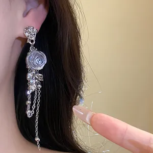 Close-up view of silver-plated resin rose earrings featuring long chain tassels on ear.