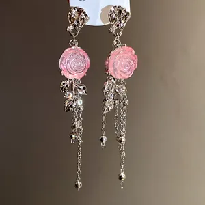 Detailed view of pink resin rose tassel earrings with silver chains and leaves