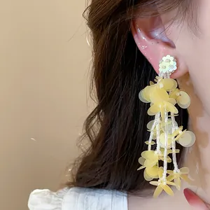 Detailed view of elegant yellow flower petal tassel earrings worn on a model's ear.