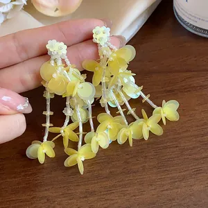 Macro view of elegant yellow floral tassel earrings featuring iridescent sequins and beads