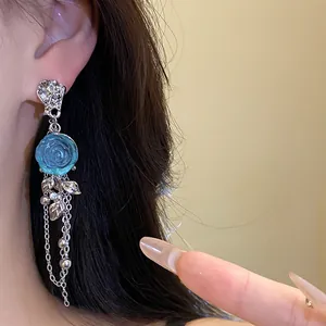 Close-up detail of elegant blue resin rose flower earrings with silver tassels