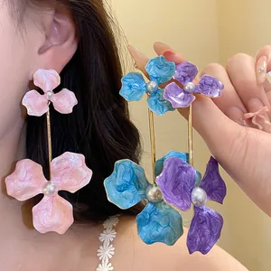 Detailansicht von übergroßen Emaille-Blumenohrringen mit Perlen an einem asiatischen Model.
