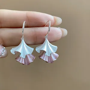 Primo piano di eleganti orecchini a foglia pieghettata con smalto bianco e rosa.