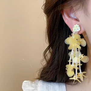 Close-up of yellow floral tassel earrings with beaded sequins on model.
