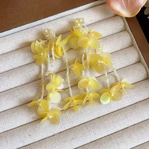 Close-up of elegant yellow petal tassel earrings displayed in a soft velvet jewelry box.