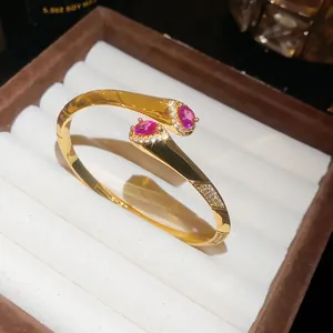 Primo piano di un bracciale rigido placcato oro 18k con zirconi rosa a goccia.