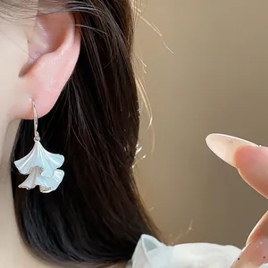 Eleganti orecchini a foglia plissettata in smalto bianco sull'orecchio della modella