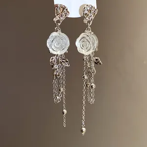 Close-up of elegant resin rose and silver tassel detailing on silver needle earrings