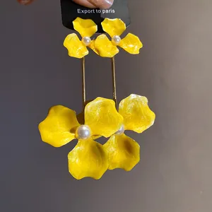 Detailaufnahme der gelben Emaille-Blumenohrringe mit eleganter weißer Perle