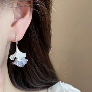 Primo piano di orecchini a foglia pieghettata con smalto blu e argento su modella