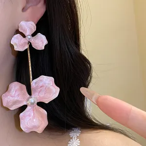 Detailansicht eleganter rosa Blumenohrringe mit Perlen und Goldstab am Model präsentiert