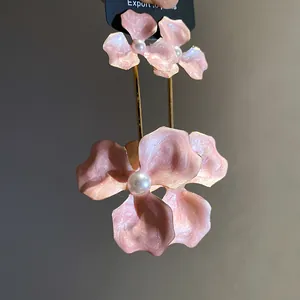 Detaillierte Nahaufnahme von rosa perlmuttfarbenen Blumenohrringen mit weißen Perlen