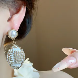 Detailed macro shot of elegant vintage oval pearl drop earrings with gold finish