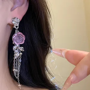 Close-up view of a pink resin rose tassel earring featuring elegant silver chains.