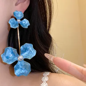 Nahaufnahme von eleganten blauen Emaille-Blumenohrringen mit weißen Perlen auf einem Model